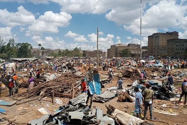Residents stand among rubble and damaged walls following the demolition of a house.