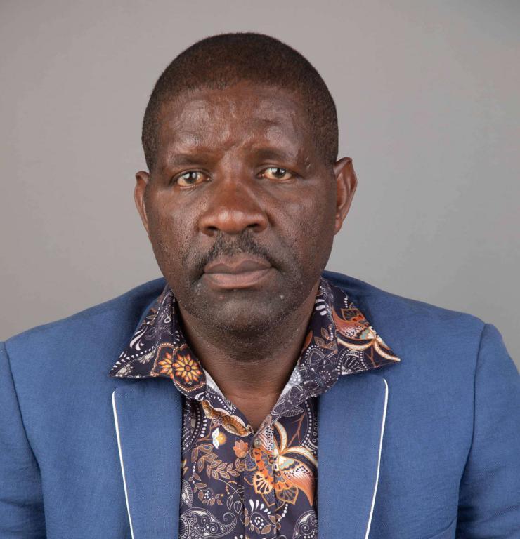 Nakuru Town East MP David Gikaria seated at a public event wearing a dark suit.