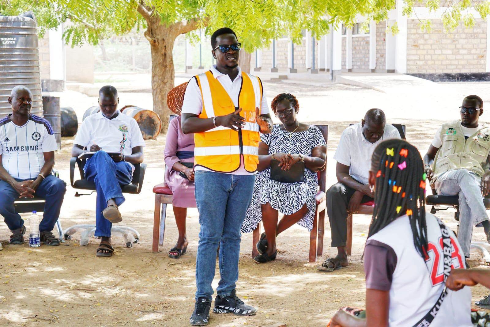 A project representative in a reflective vest addresses community members during consultations on the proposed dialysis unit in Turkana County.